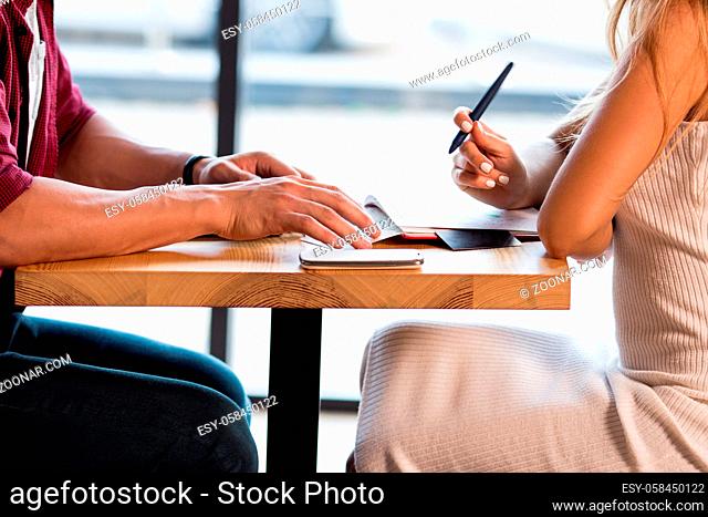Beloved Young Couple Making Notes While Sitting In Cafe. Making List Of Wedding Guests. Love story concept