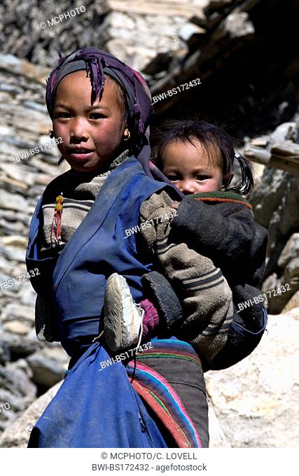 Tibetan girl carrying her sister piggyback, Nepal, Annapurna Conservation Area, Phu Village