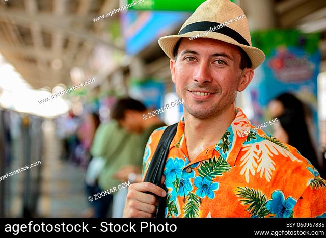 Portrait of young handsome tourist man at sky train station in the city