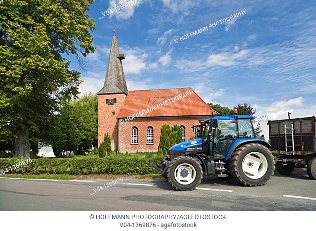 The historic brick church of Staffhorst and a blue tractor, Lower Saxony, Germany, Europe