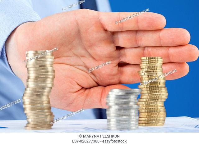 Businessman pushing away column from euro coins, closeup shot