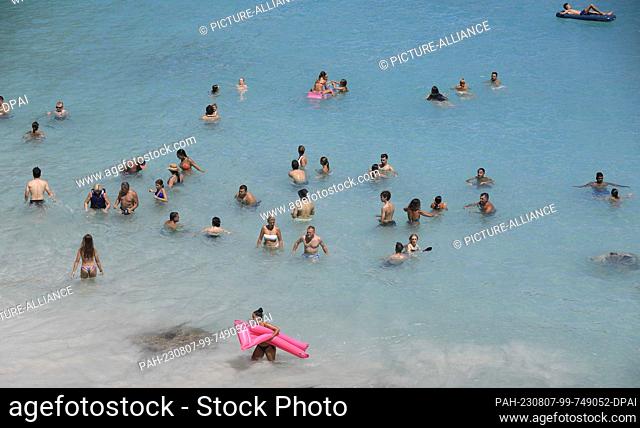 06 August 2023, Spain, Santanyi: People bathing in the sea at Calo des Moro beach in Mallorca, one of the most crowded beaches in Mallorca