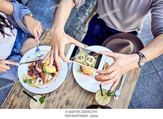 Overhead view of couple taking photo of food at outdoors restaurant