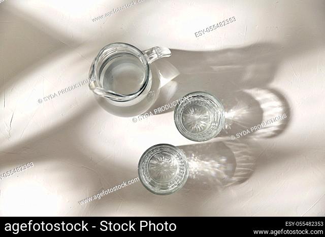 two glasses and jug with water on white background
