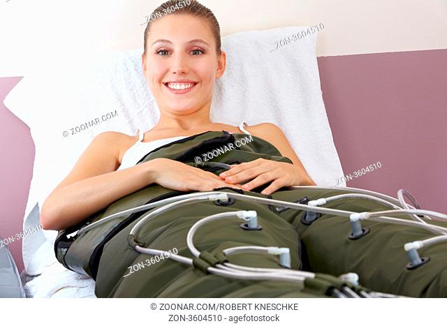 Lachende Frau bei Druckwellenmassage im Fitnesscenter zur Fettverbrennung