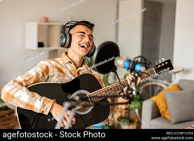 Happy man singing and playing guitar at home