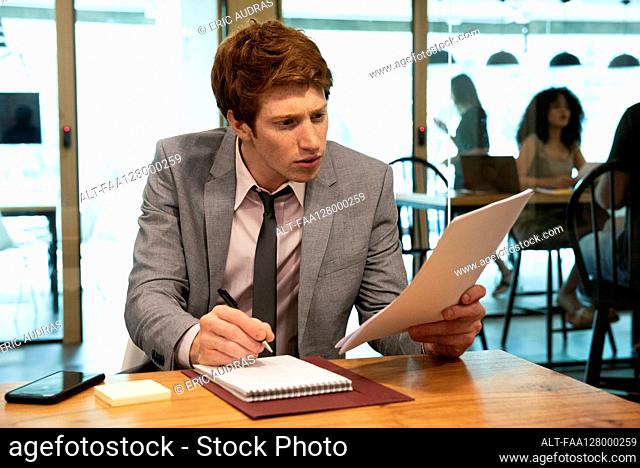 Young businessman writing on notebook in office