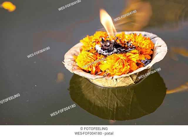 India, Uttar Pradesh, Leaf bowl with oil lamp floating on river Ganges