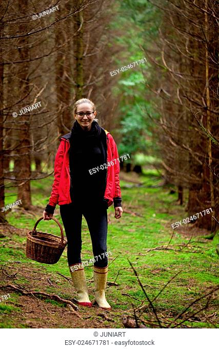 young woman collecting mushrooms in forest autumn nature