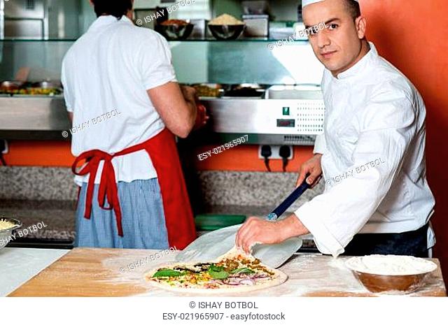 Chef giving last touches to vegetable pizza