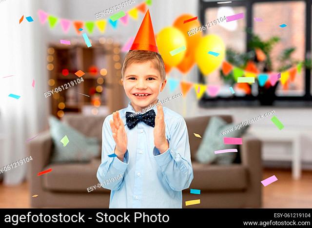 smiling boy in birthday party hat applauding