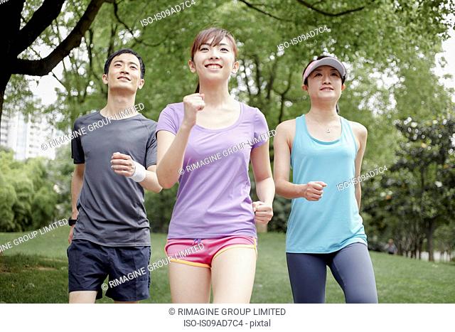 Three young people jogging in park