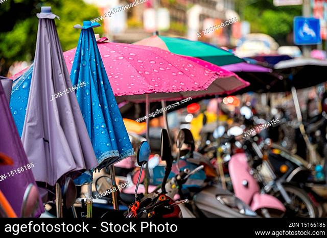 Yangshuo, China - August 2019 : Row of small motorbikes and scooters parked on a street in Yangshuo town, Guangxi Province