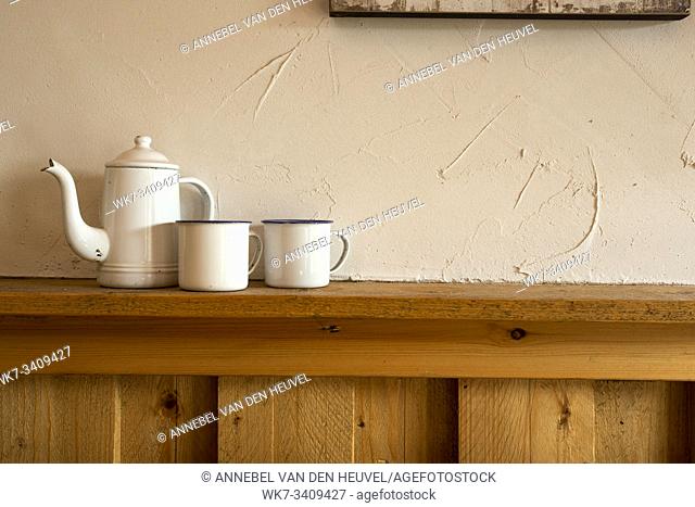 Old vintage teapot and two cup of tea on wooden shelf, antique interior