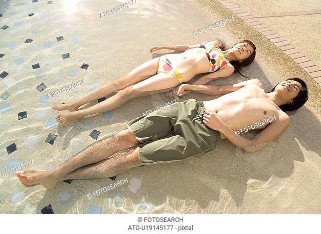 Young couple lying in swimming pool, Saipan