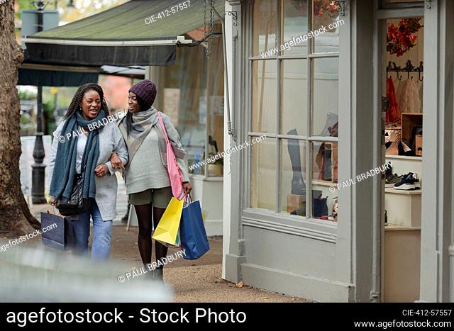 Happy mother and daughter walking arm in arm with shopping bags