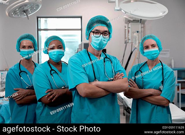 Diverse group of male and female doctors standing in operating theatre wearing face masks