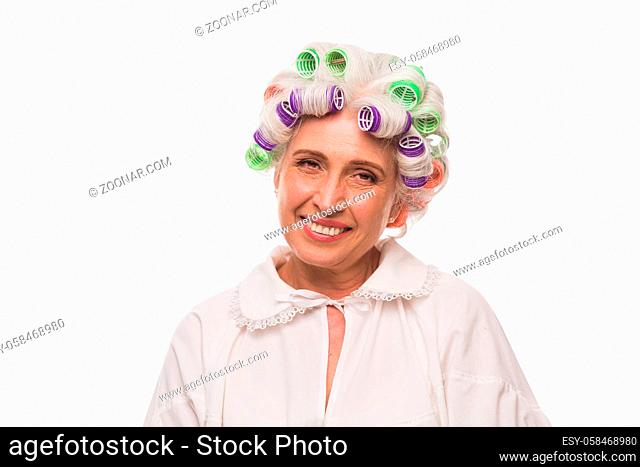 Happy smiling beautiful senior lady looking at camera. Pretty grandmother with rollers on posing in studio for photographer