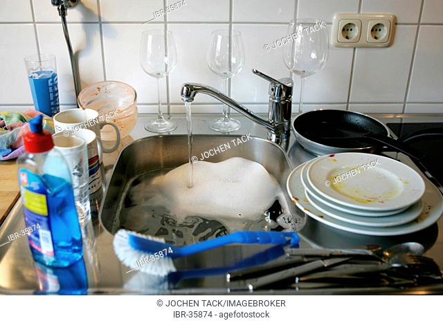 DEU, Germany: Cleaning of dishes by hand in a private kitchen