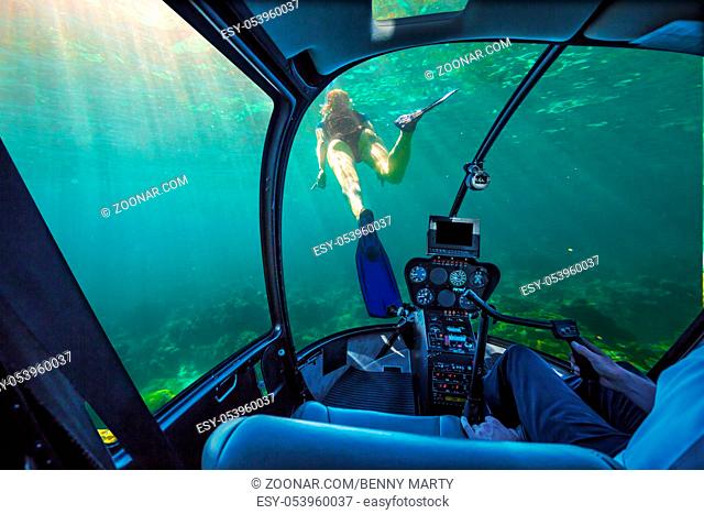 Underwater submarine ship following a young female snorkeling in tropical sea. Woman apnea swims in coral reef with sunbeams. cockpit interior view