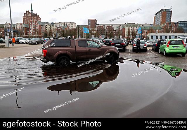 14 December 2023, Mecklenburg-Western Pomerania, Rostock: A car drives through a large puddle in the city harbor. The thawing and rainy weather of the past few...
