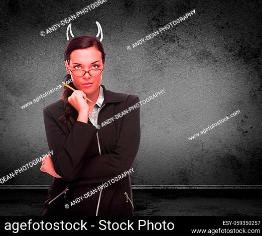 Devil Horns Drawn on Head of Red Faced Young Adult Woman with Pencil In Front of Grungy Wall with Copy Space