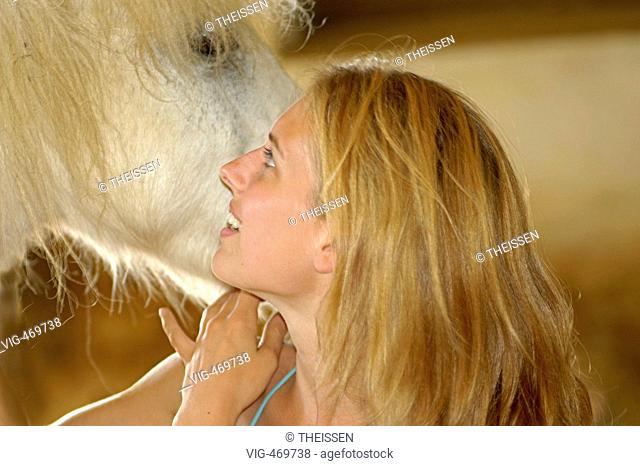 young blonde fondling a white horse. - 01/01/2007