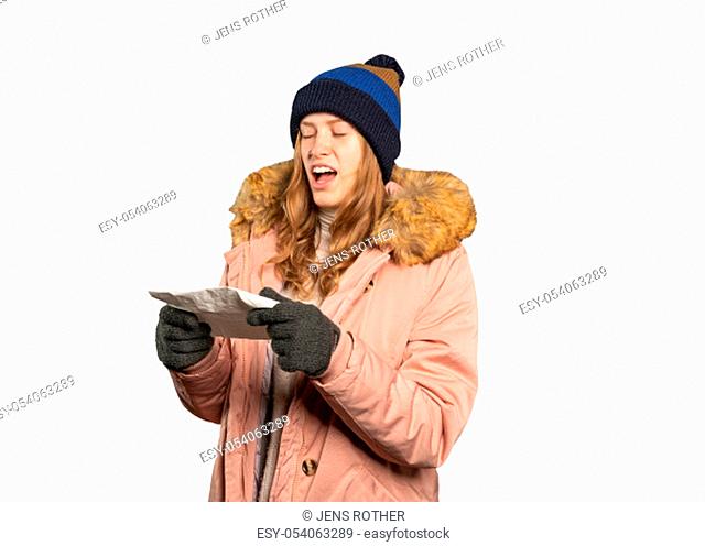 A young woman in winter clothes is holding a handkerchief and has to sneeze