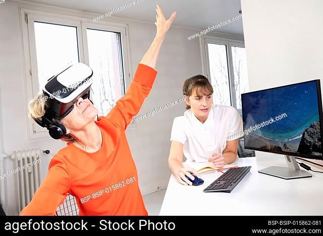 Elderly woman, during a therapy session with a virtual reality headset under the supervision of a therapist