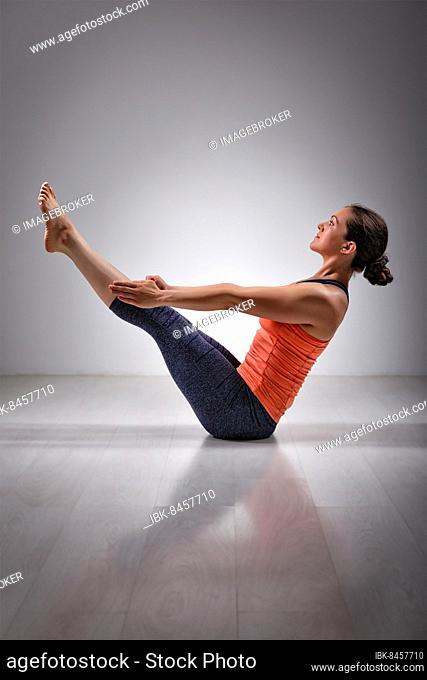 Beautiful sporty fit yogini woman practices yoga asana Paripurna navasana, boat pose
