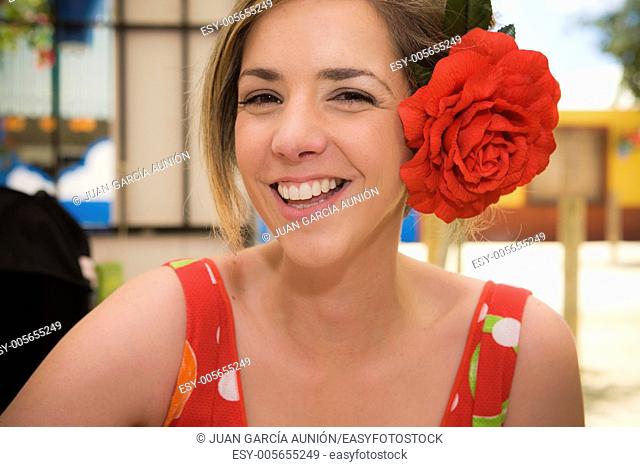 Young woman with gipsy dress and red flower on head at Cordoba Fairground, Spain