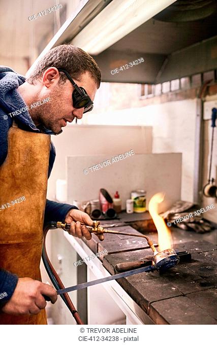 Jeweler heating metal using torch in workshop