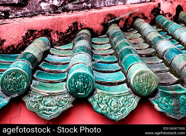 Impression with brilliant decoration on roof of temple with Chinese style, yin and yang tile, ancient texture and roof top in red and cyan at Ho Chi Minh city