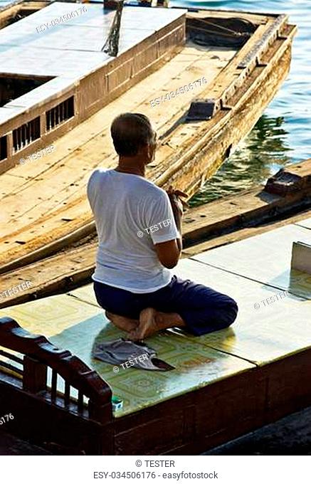 DUBAI, UAE-NOVEMBER 13: An unidentified man - boatman sitting in a boat and prays on November 13, 2012 in Dubai, UAE