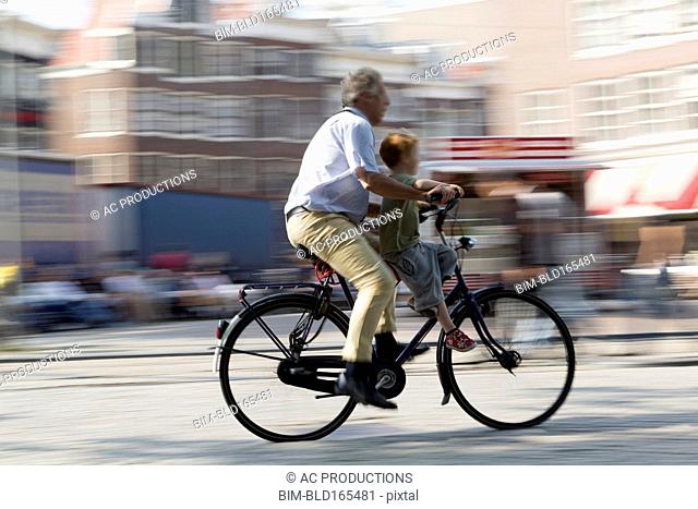 Blurred view of father and son bicycling on city street