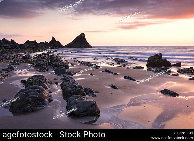 The exposed beach during low tide at Hartland Quay in the North Devon Area of Outstanding Natural Beauty at dusk, England
