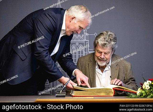 23 November 2023, Thuringia, Erfurt: The Lord Mayor of the City of Erfurt, Andreas Bausewein (SPD), shows Reinhold Messner an entry in the Golden Book of the...