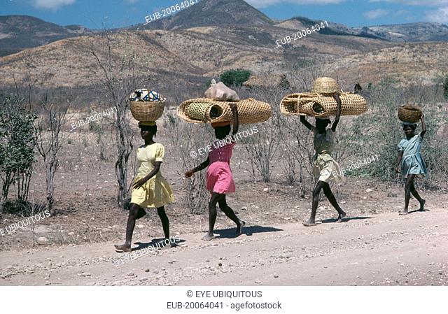 Line of girls carrying bags and baskets on their heads