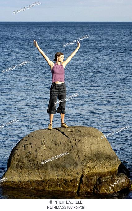A woman standing on a cliff by the sea, Vaddo, Stockholm archipelago, Sweden