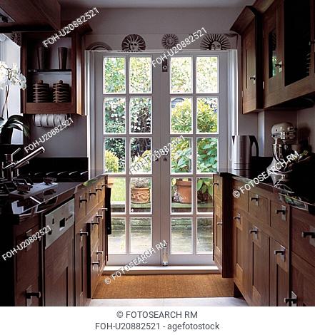 Glazed French doors in traditional galley kitchen with wooden fitted cupbaords