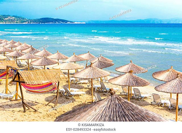 Summer greek beach vacation background with turquoise sea water waves and umbrellas, Greece