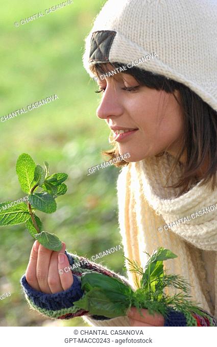 HEALTH AND PLANTS. YOUNG WOMAN IN THE OUTDOORS WITH A BUNCH OF HERBS