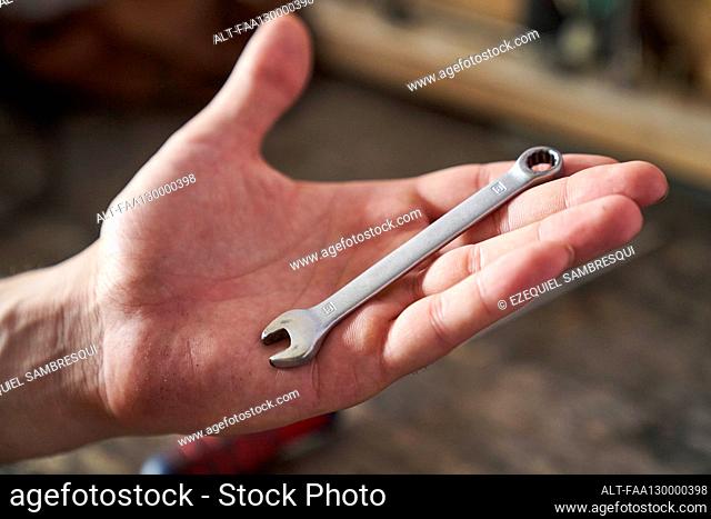 Close-up shot of combination spanner on the palm of a person's hand