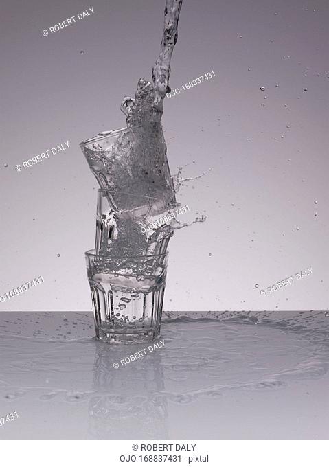 Water pouring into stacked glasses