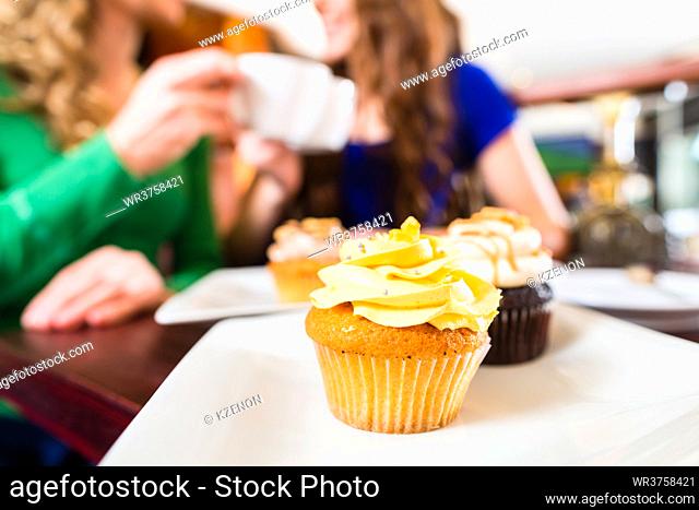Friends having fun and eating muffins at bakery or pastry shop