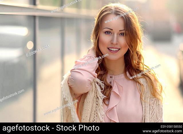 Happy young woman laughing towards the camera in early morning sunlight outdoors with copy space tho the left
