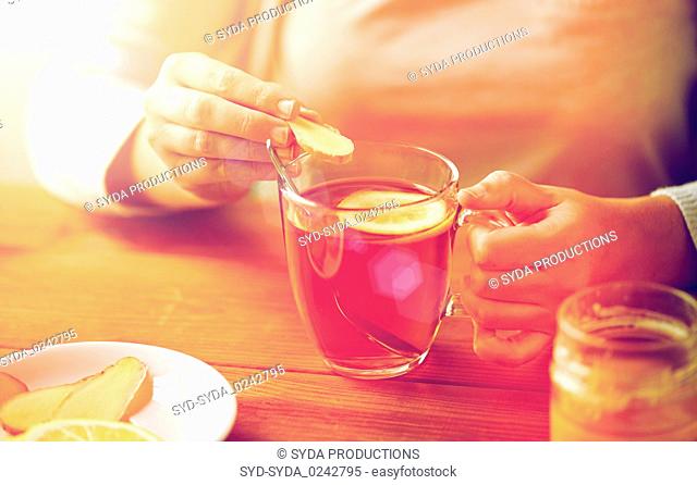 close up of woman adding ginger to tea with lemon