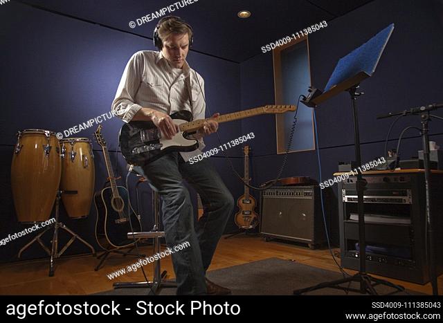 Caucasian man playing guitar in studio