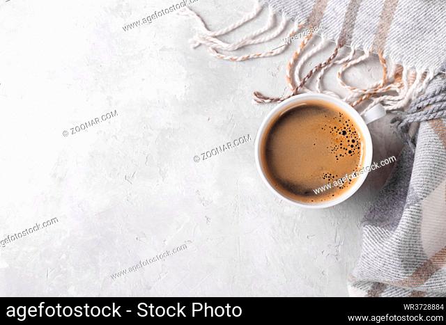 Cup of hot coffee and checkered plaid on grey stone background copy space flat lay top view