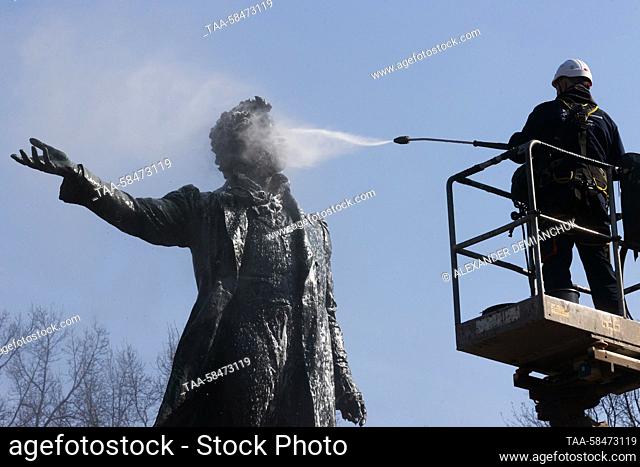 RUSSIA, ST PETERSBURG - APRIL 17, 2023: A utility worker washes a statue of Russian poet Alexander Pushkin in Arts Square by the Mikhailovsky Palace